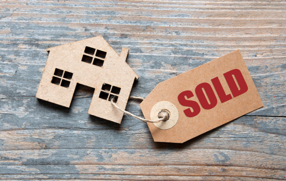 A small cardboard house with a SOLD tag attached